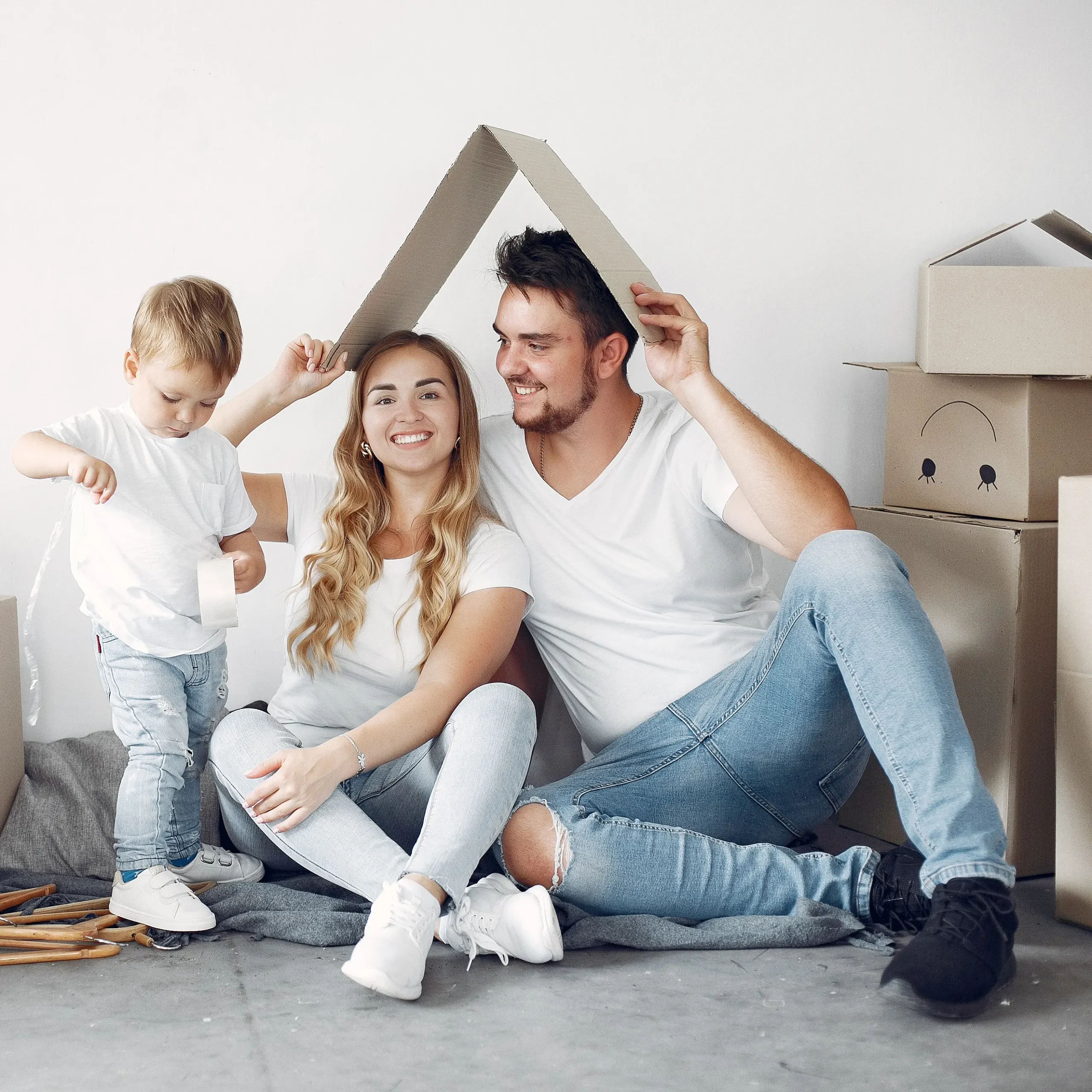 Familia realizando una mudanza y haciendo la forma de un tejado con cajas de carton