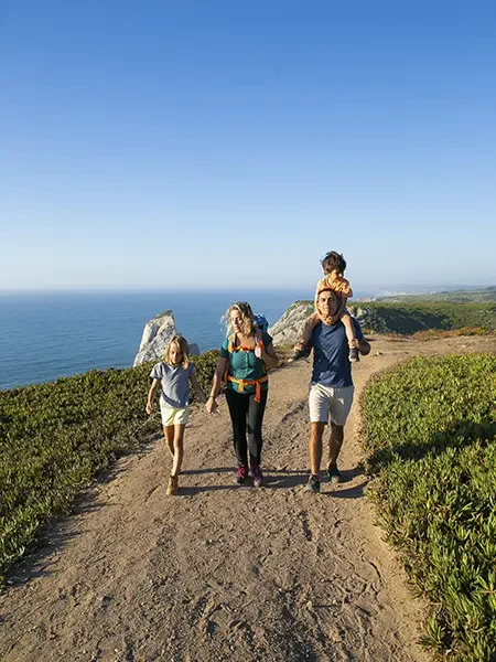 Familia con dos hijos paseando por un camino cerca del mar