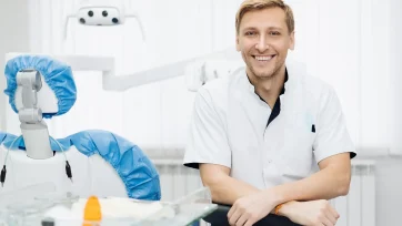 Dentista sonriente en su consulta con los brazos relajados