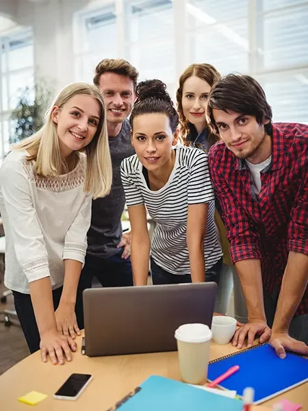 Grupo de trabajadores en una oficina delante de un portatil y con las manos apoyadas sobre la mesa